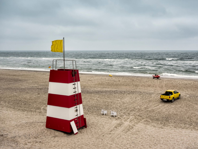 Fuente: Canva. Puesto de socorrismo y bandera amarilla en una playa. Permitido el baño pero con precaución.